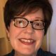 A white woman with short hair wearing glasses